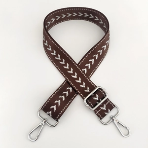 Close-up of adjustable brown nylon bag strap with white arrow pattern and silver hardware