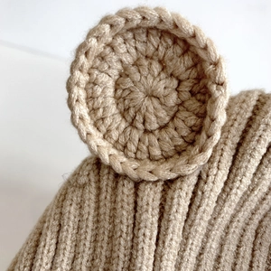 Nahaufnahme der Strickmütze mit hellbrauner Wollstruktur und gehäkelten Bärenohr-Details