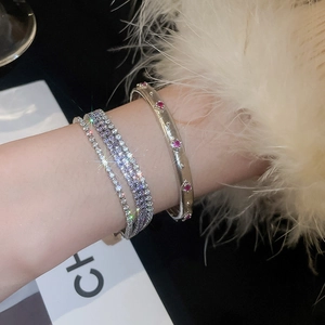 Detail eines mehrlagigen silbernen Armband-Sets mit roten Steinen und Sternanhängern