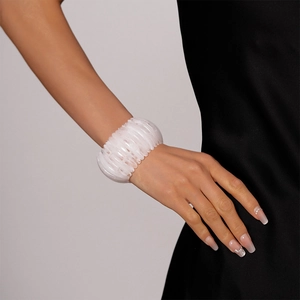 Gros plan d'un large bracelet en acrylique blanc translucide à texture plissée sur le poignet