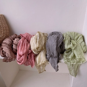 Vintage pleated silk-feel scarves in assorted earth tones displayed on a white wall