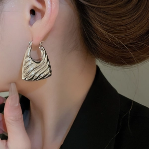 Detail of silver wavy textured earring with liquid metal finish on a model