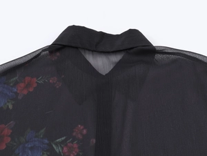 Dettaglio camicia in chiffon nero velato con stampa floreale e colletto su bianco