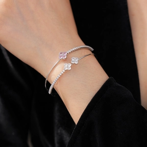 Close-up of silver-tone clover bangle with shimmering zircon stones on a black background