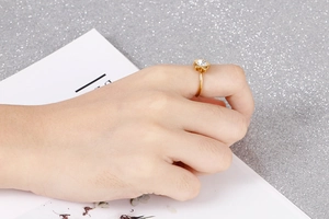 Macro detail of a gold flower zircon ring featuring a central crystal on a female index finger