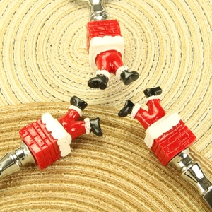 Detailed view of Santa chimney wine stoppers on woven mat with metal and resin finish