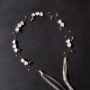 Macro detail of handmade bridal headband with white flowers, pearls and gold wire