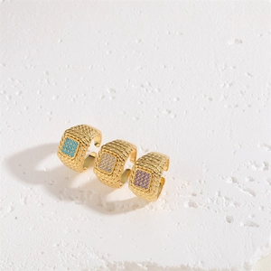 Three vintage gold woven rings with square turquoise, white, and purple gemstones set on white