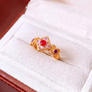 Vintage 24K gold plated flower ring with red stone and purple accents on white velvet