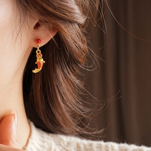Gros plan d'une boucle d'oreille carpe koi dorée avec accents rouges sur un mannequin