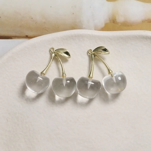 Detail of transparent cherry pendants with gold leaves for DIY jewelry making
