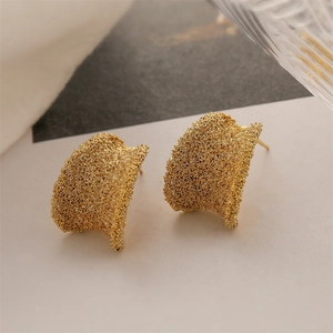Detailed view of golden semi-circular earrings with a brushed textured metallic finish