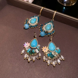 Detail of bohemian drop earrings featuring turquoise stones, pearls, and golden tassels