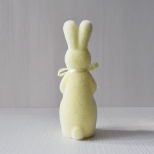 Rear view of light yellow flocked Easter rabbit figurine with a matching ribbon detail