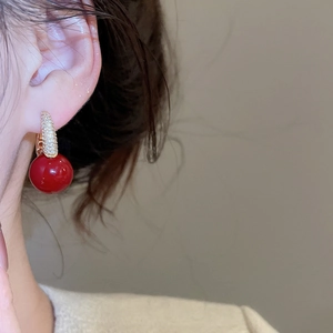 Close-up of elegant red round resin earring with gold cubic zirconia pavé hook