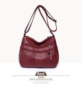 Detail of red multi-pocket shoulder bag featuring layered zippers and soft PU leather