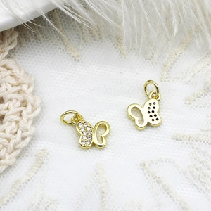 Macro shot of gold butterfly charms with white zircon inlay on white lace background