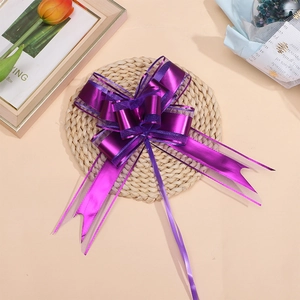 Close-up of a double-layered purple gift bow with matte metallic ribbons on a woven mat
