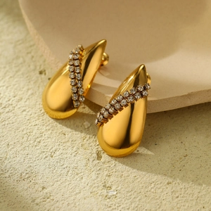 Detail view of gold teardrop earrings with pavé rhinestones on stone background