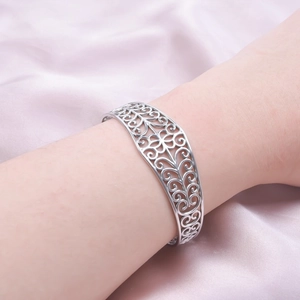 Close-up of silver open cuff bracelet with hollow wave pattern on model's wrist