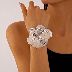 Detail of silver metallic flower cuff bracelet with irregular wrinkled texture on wrist