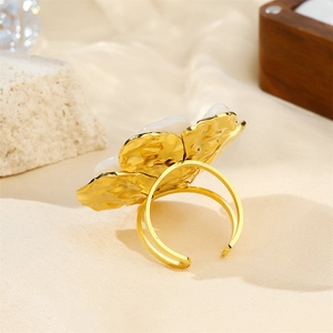 Detailed shot of 18k gold butterfly ring with white shell flower on silk