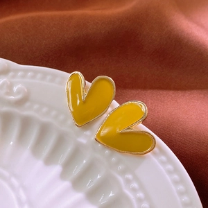 Detail of ginger yellow heart earrings with gold trim on white ceramic tray