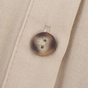 Makroaufnahme des Leinenmischgewebes und der Bernstein-Knopfdetails am ärmellosen Kleid