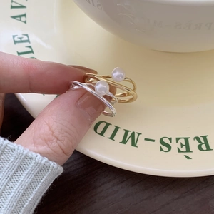 Macro shot of 925 silver pearl rings in gold and silver finish on a ceramic plate