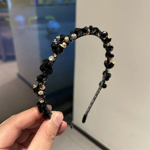 Close-up of black crystal bead headband with gold hollow floral accents and white rhinestones