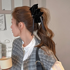 Elegant black velvet bow hair clip with long ribbons shown on a ponytail hairstyle