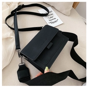 Detail view of black square crossbody bag with interchangeable wide and thin straps