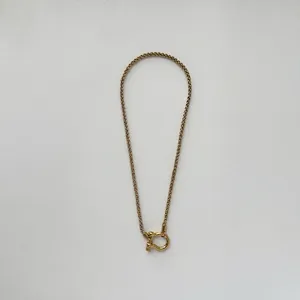 Detailed macro view of 18K gold plated wheat chain with horseshoe shackle clasp closure