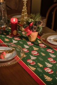 Green Christmas table runner with Santa Claus pattern on a wooden table with decor