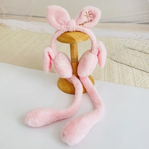 Detail of pink plush rabbit ear muffs featuring golden smile embroidery and sun pattern