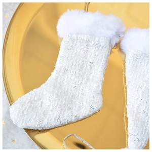 Detail of tweed Christmas stocking with white faux fur trim on a gold reflective tray