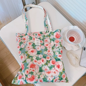 Detail of floral canvas tote bag with pink rose prints and white woven strap handles
