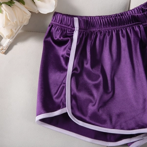 Close-up of purple satin sports shorts with white piping and smooth silky texture