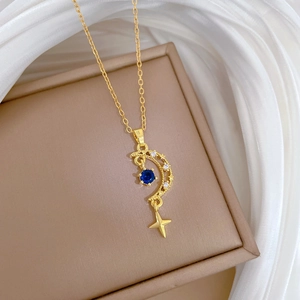 Star and moon gold necklace with blue gems on silk background in a jewelry box