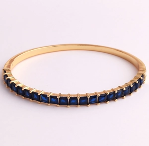 Detail of 18K gold-plated cuff featuring a row of square blue zircon stones on metal