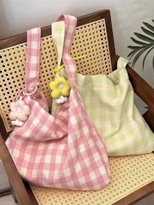 Checkered canvas tote bags in pink and green with floral charms on a vintage chair