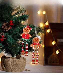 Detail of wooden gingerbread couple ornaments with long bead legs on Christmas tree branches