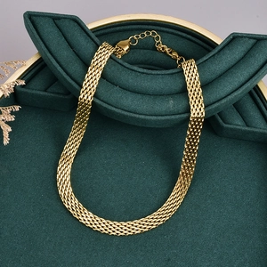 Collana a maglia dorata presentata su un supporto per gioielli in velluto verde scuro