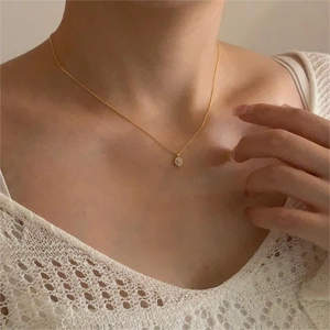 Close-up of minimalist gold zircon necklace on neck with elegant white lace details