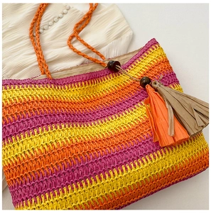 Detail of colorful woven straw tote with rainbow stripes, wooden beads, and tassels