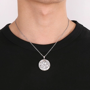Vue détaillée du collier avec pendentif Saint Benoît en argent porté par un mannequin homme