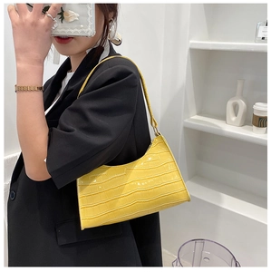 Detail of yellow crocodile pattern leather bag with metallic zipper and shoulder strap