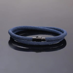 Detailed view of blue braided cord bracelet with black magnetic clasp on reflective surface