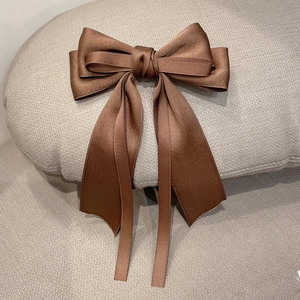 Detail of coffee brown satin bow hair clip with elegant long ribbons and silky texture