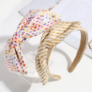 Fashionable woven bow headbands in colorful and brown patterns displayed on a book